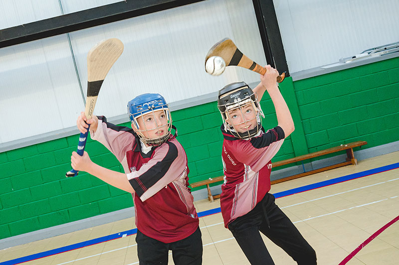 Moyderwell Mercy National School students playing hurling in gym